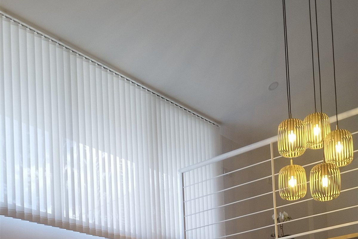 Estores verticales blancos en un salón de doble altura