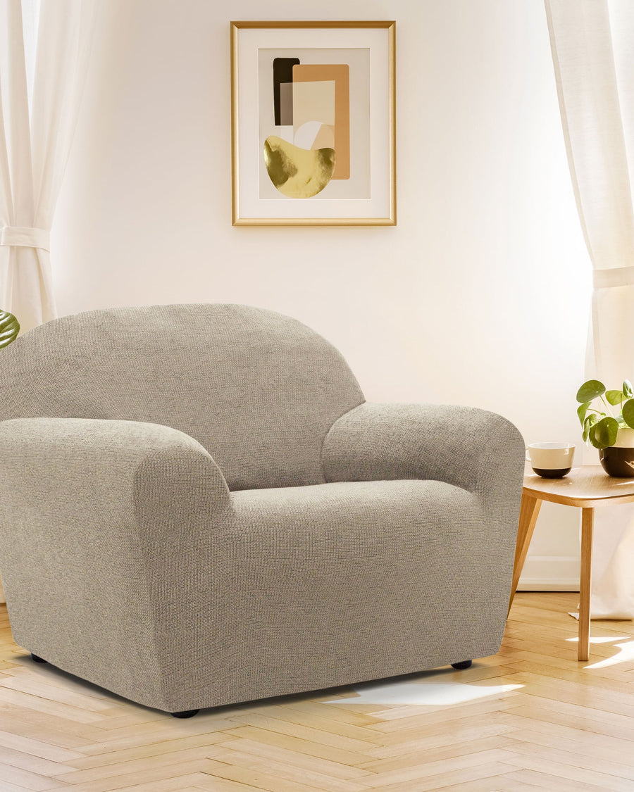 Sillón con funda elástica Soraya Pocket beige en un salón luminoso